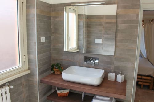 Bagno moderno nella Lilla Suite di Maison Tizi a Roma con lavabo in ceramica, mobile in legno e piastrelle grigie