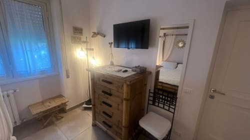 Camera LILLA Suite a MAISON TIZI a Fiumicino Roma con cassettone in legno, TV, specchio e illuminazione moderna