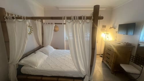 Suite LILLA presso MAISON TIZI con letto a quattro colonne, tende bianche, mobili in legno, TV e illuminazione calda a Fiumicino Roma