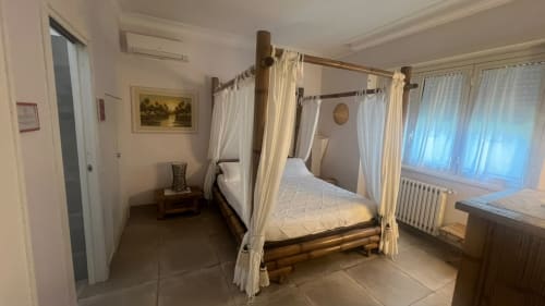 Elegante letto a baldacchino nella Suite LILLA di Maison Tizi, Fiumicino Roma con vista sul giardino e finestre luminose