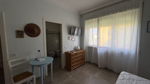 Suite Acquamarina presso MAISON TIZI con tavolo da pranzo, cassettone in legno, TV e vista giardino attraverso tende leggere
