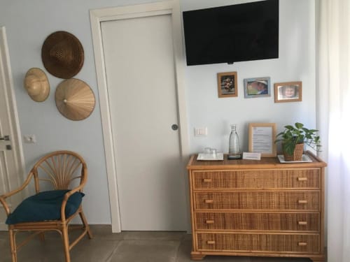 Suite Acquamarina presso MAISON TIZI: sedia in rattan, cassettone in legno, TV a muro e cesti decorativi a Fiumicino