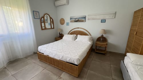 Camera Acquamarina di MAISON TIZI con letto in rattan intrecciato, biancheria bianca, pavimenti piastrellati e vista giardino a Fiumicino