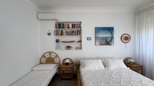 Camera da letto gemella luminosa a Maison Tizi con letti bianchi, comodini in legno, libreria e opere d'arte tematiche marine a Roma