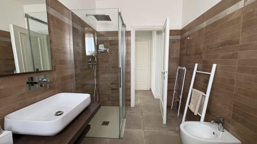 Bagno moderno presso MAISON TIZI Lovely Suites a Roma con rivestimenti in piastrelle marrone, sanitari bianchi, doccia a filo e riscaldamento