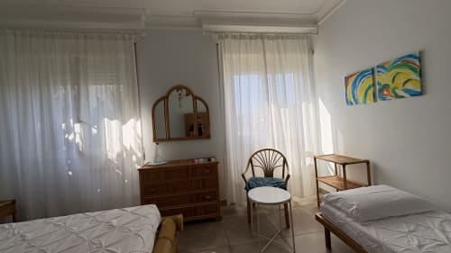 Camera da letto gemellare luminosa con arredamento in legno, tendaggi bianchi e decorazioni murali colorate presso MAISON TIZI Turchese Suite