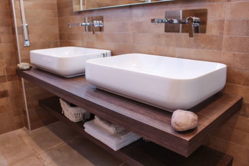 Bagno moderno della Turchese Suite presso MAISON TIZI con due lavabi bianchi su vanità in legno scuro e pareti in cotto