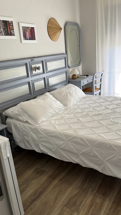 Camera Gardenia Suite presso MAISON TIZI con biancheria bianca, testata grigia, comodino e specchio a Passoscuro Fiumicino Roma