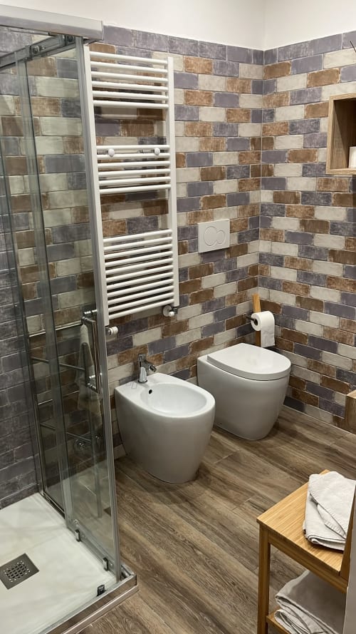 Bagno moderno nella Gardenia Suite di MAISON TIZI con doppi wc, bidet, portasciugamani bianco, piastrelle multicolori e