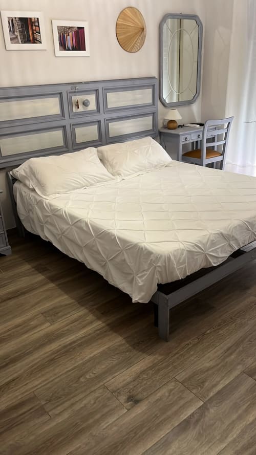 Camera moderna di MAISON TIZI con testata grigia, biancheria bianca, pavimento in legno, scrivania e specchi a parete nella Suite Gardenia