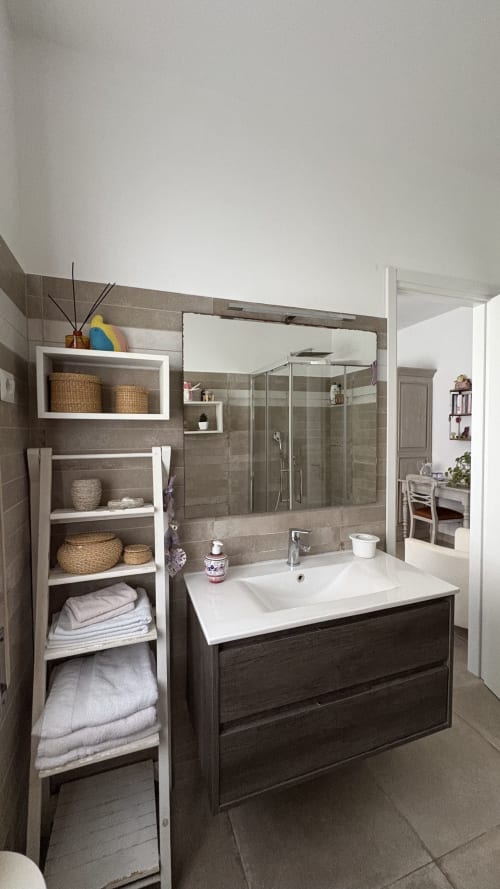Bagno moderno nella Suite Magnolia di MAISON TIZI B&B con piastrelle scure, lavabo bianco, box doccia in vetro e spazio aperto