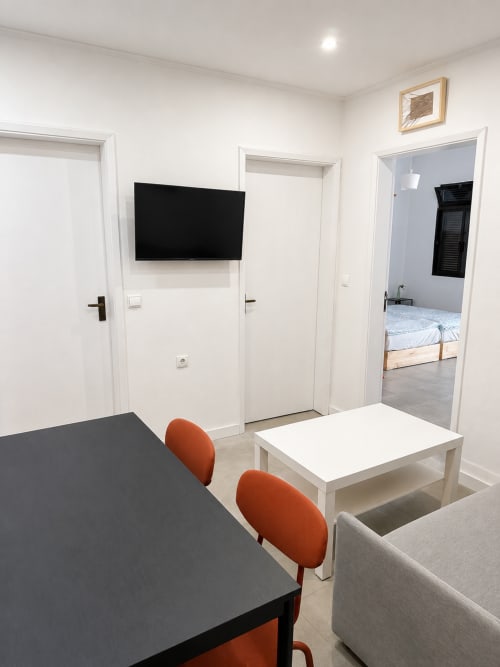 Sala de estar moderna em Villas Simone Porto Santo com mesa de jantar, cadeiras laranja, TV na parede e vista para o quarto