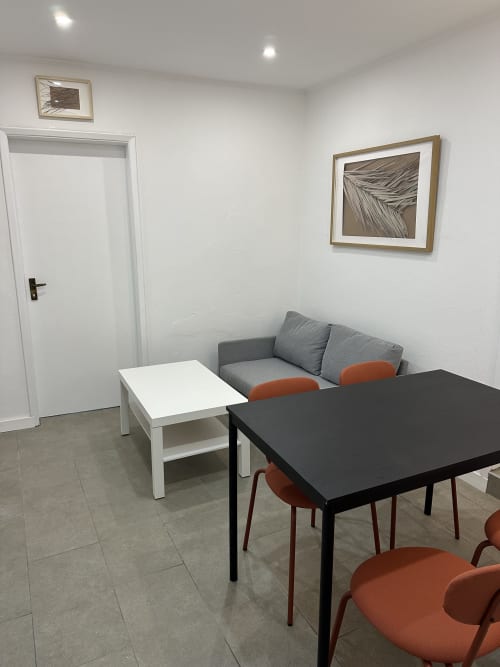Sala de estar moderna no Apartamento Família Garden da Villas Simone Porto Santo com sofá cinzento, mesa de jantar e parede botânica