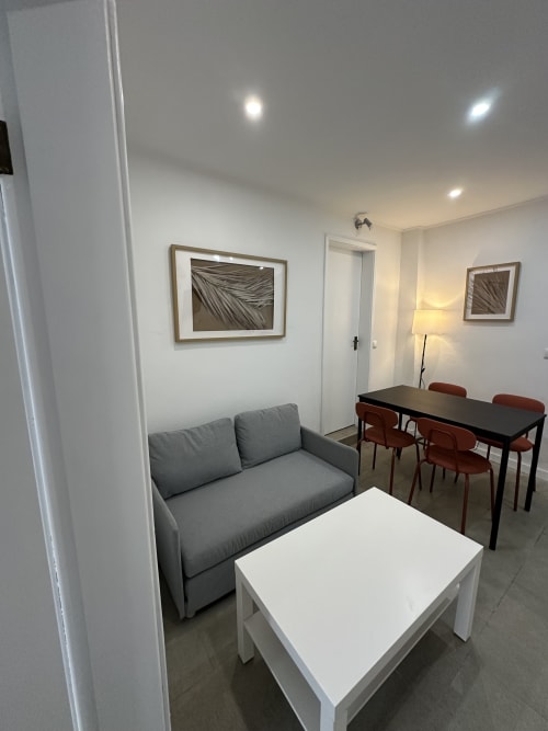 Espaço de convivência moderno em Villas Simone Porto Santo com sofá cinzento, mesa branca, zona de refeições e arte emoldurada na parede