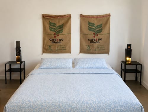 Quarto com roupa de cama azul na Villas Simone Porto Santo, apresentando arte de painel de café e mesas de cabeceira pretas