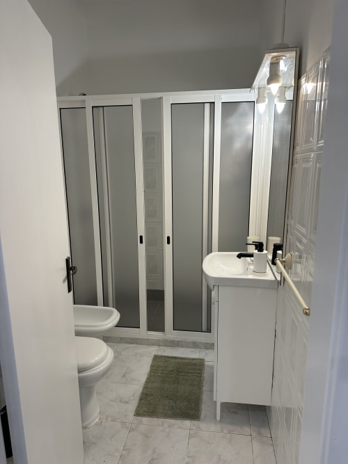 Banheiro moderno em Villas Simone Porto Santo com fixtures brancos, piso em mármore e box de vidro