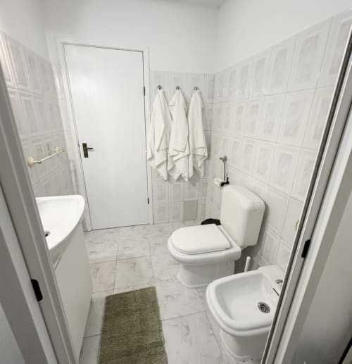 Banheiro moderno com azulejos brancos, vaso sanitário, bidê e chuveiro nas Villas Simone Porto Santo City & Beach Apartments