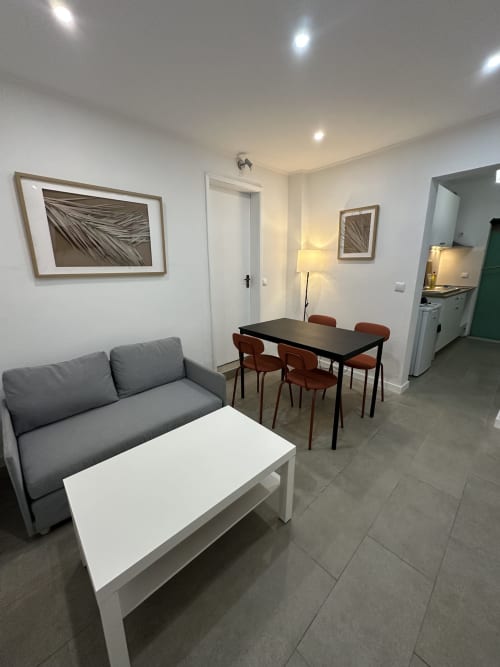 Área de estar do Apartamento Garden Family em Villas Simone Porto Santo, com sofá cinza, mesa de jantar e cozinha americana