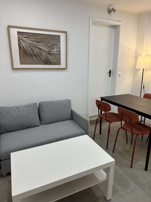 Área de estar moderna no Apartamento Família Garden da Villas Simone Porto Santo com sofá cinzento, mesa branca e cadeiras de refeição