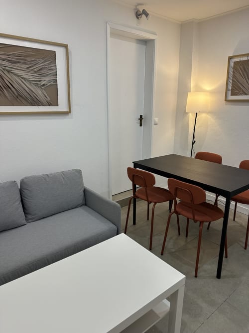 Sala de estar moderna no Apartamento Family Garden da Villas Simone Porto Santo com sofá cinzento, mesa de jantar e tons de terracota