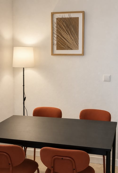 Moderna área de refeições em Villas Simone Porto Santo com mesa preta, cadeiras cor ferrugem, luminária de piso e arte abstrata na parede