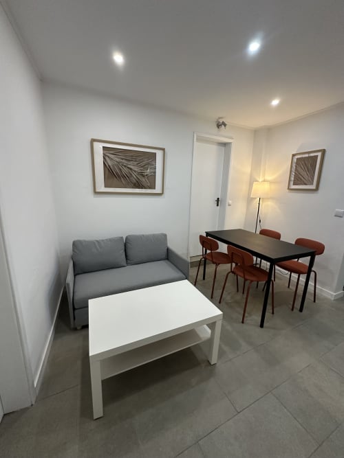 Espaço de estar moderno no Apartamento Family Garden da Villas Simone Porto Santo com sofá cinza, mesa de jantar e obras de arte