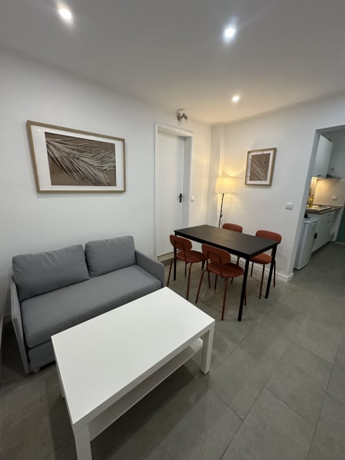 Moderna área de estar em Villas Simone Porto Santo com sofá cinza, mesa de jantar e cozinha no apartamento familiar do jardim