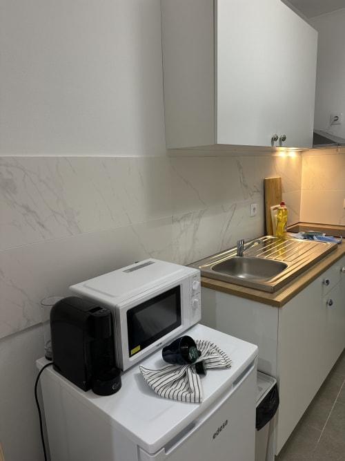 Cozinha compacta em Villas Simone Porto Santo com micro-ondas, pia, fogão e eletrodomésticos brancos