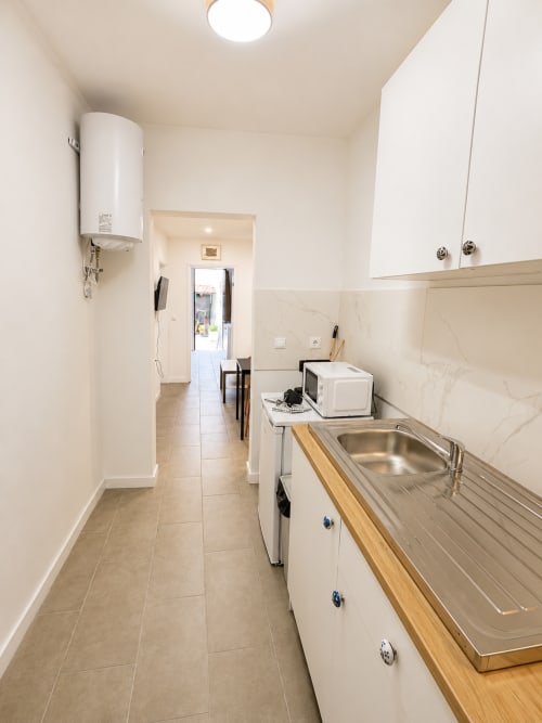 Cozinha em galera moderna na Villas Simone com armários brancos, pia em aço inoxidável, bancada em madeira e eletrodomésticos