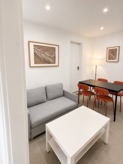 Sala de estar do apartamento Family & Friends em Villas Simone Porto Santo com sofá cinzento, mesa branca e zona de refeições laranja