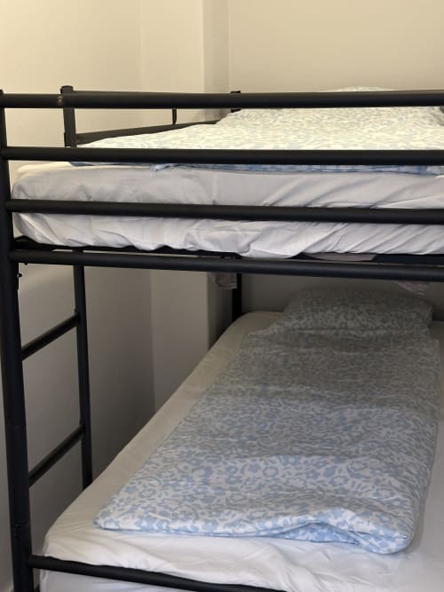 Camas beliche de metal preto com roupas de cama brancas e estampadas nas Villas Simone Porto Santo City & Beach Apartments