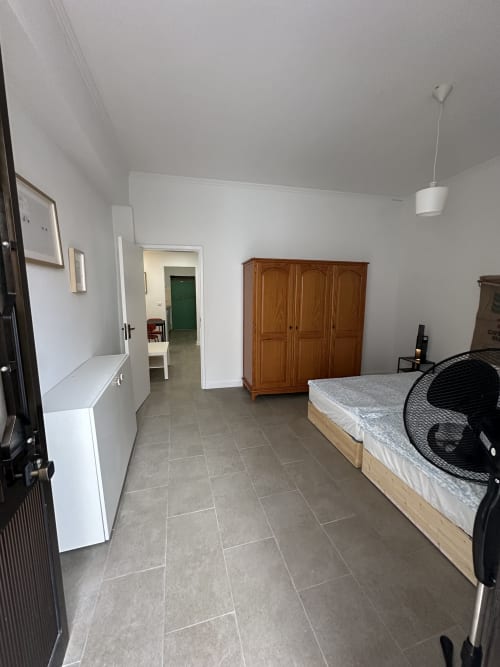 Quarto espaçoso nas Villas Simone Porto Santo com guarda-roupa de madeira, cama, escrivaninha e piso em azulejo