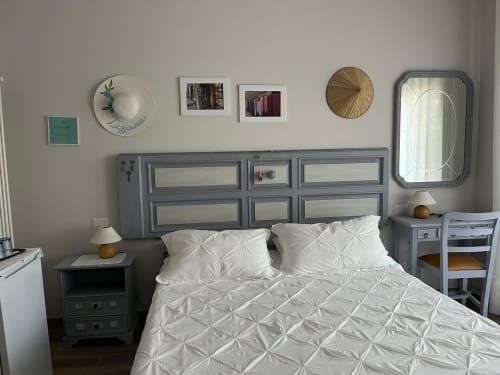 Camera moderna a Maison Tizi con biancheria bianca, testata grigia, specchi e decorazioni murali a Fiumicino Roma