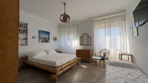 Camera luminosa alle Maison Tizi Lovely Suites a Fiumicino Roma con letto in legno, specchio e grandi finestre