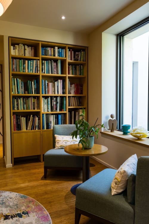 Salon bibliothèque moderne du Domaine de la Peyrine avec bibliothèque en bois, sièges confortables et grandes fenêtres avec vue
