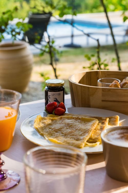 Petit-déjeuner en plein air au Domaine de la Peyrine : crêpes, fraises fraîches, jus d'orange et pot de confiture avec vue