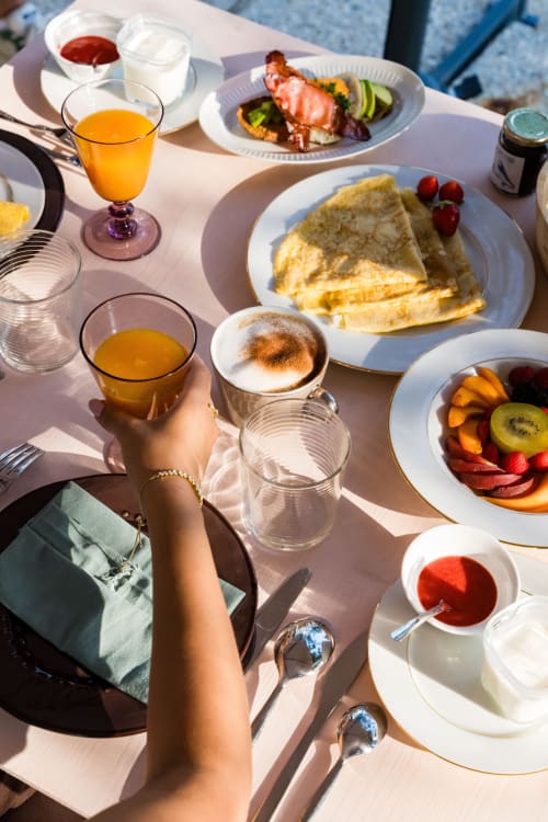 Petit-déjeuner au soleil au Domaine de la Peyrine : crêpes, fruits frais, jus d'orange et pâtisseries avec vue sur Carignan de Bordeaux