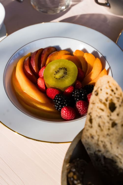 Élégant plateau de fruits au Domaine de la Peyrine avec kiwis, abricots, framboises et baies sur fine porcelaine blanche