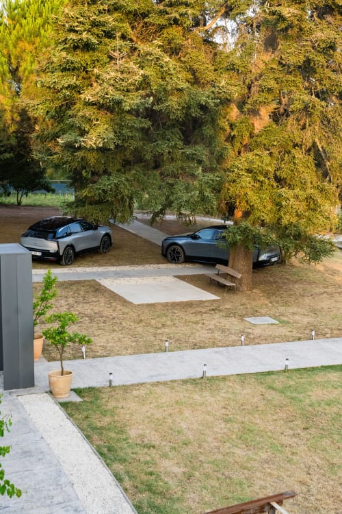 Véhicules électriques modernes garés sous des arbres matures au Domaine de la Peyrine à Bordeaux