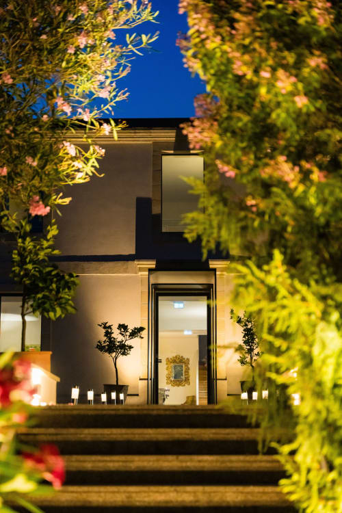 Entrée moderne du Domaine de la Peyrine illuminée la nuit avec plantes fleuries et ciel étoilé