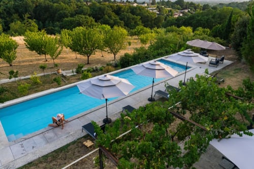 Vue aérienne de la piscine du Domaine de la Peyrine avec parasols blancs, transats et vignobles environnants à Carignan