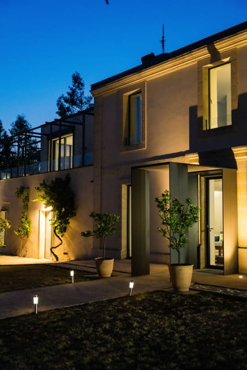 Façade élégante du Domaine de la Peyrine à Carignan de Bordeaux au crépuscule, illuminée par une lumière chaleureuse