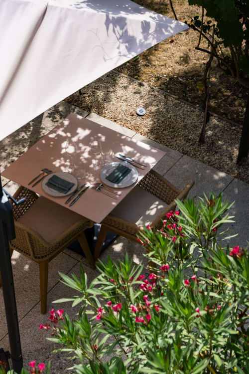 Table de restaurant élégante à Domaine de la Peyrine avec couverts, auvent blanc et fleurs roses à Carignan