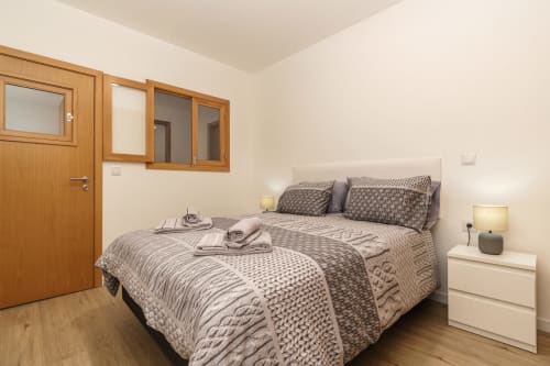 Spacious bedroom at Michaels Garden apartment in Estreito da Calheta with double bed, wooden door, wall cabinets, and garden