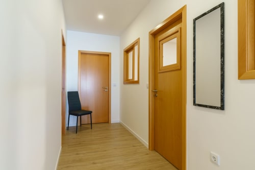 Modern hallway at Michaels Garden apartment with wooden doors, flooring, and chair access