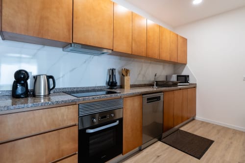 Modern kitchen in Michaels Garden apartment at Garry's Holiday Rentals with wooden cabinets, granite countertop, and
