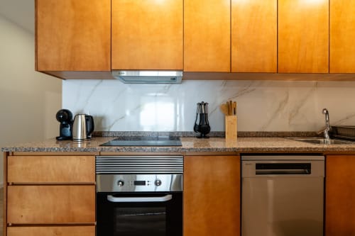 Modern kitchen with wooden cabinets, granite countertop, stainless steel appliances, marble backsplash at Michaels Garden