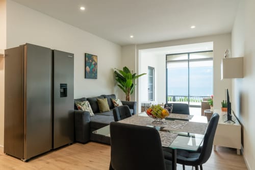 Modern living area at Michaels Garden apartment in Estreito da Calheta with sofa, dining table, kitchen, and garden views