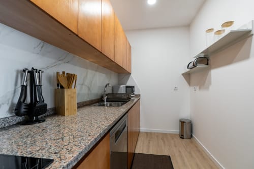 Modern kitchen in Michaels Garden apartment at Garry's Holiday Rentals with wooden cabinets, granite countertop, and
