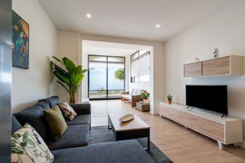 Modern living room at Michaels Garden apartment in Estreito da Calheta with sofa, flat-screen TV, and garden view balcony